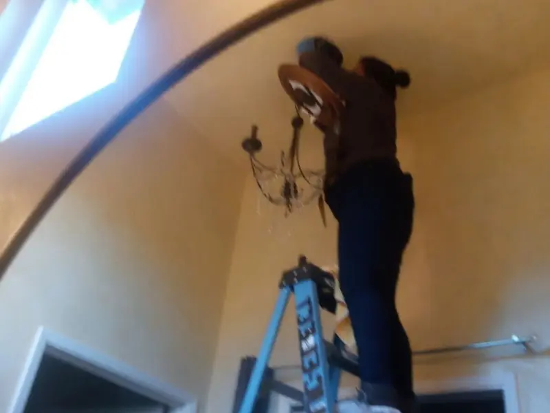 Electrician installing a chandelier in a Savage residence